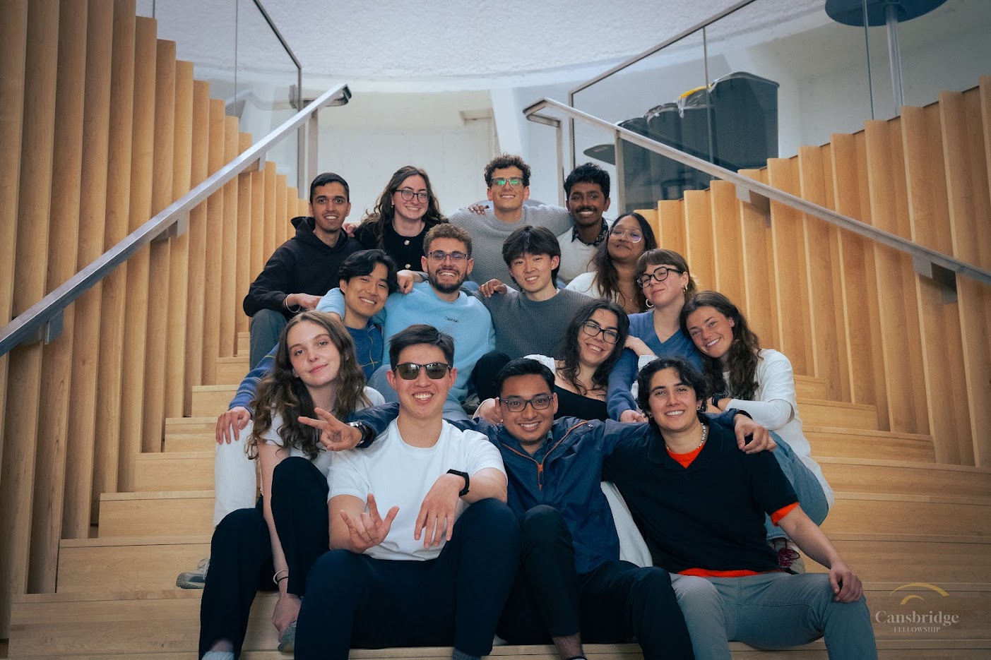A group of students sit in rows on steps, smiling at the camera