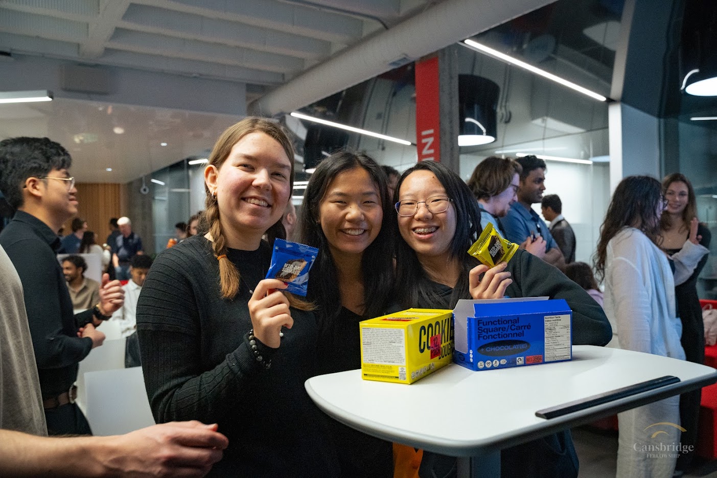 Students hold up snacks as they smile at the camera