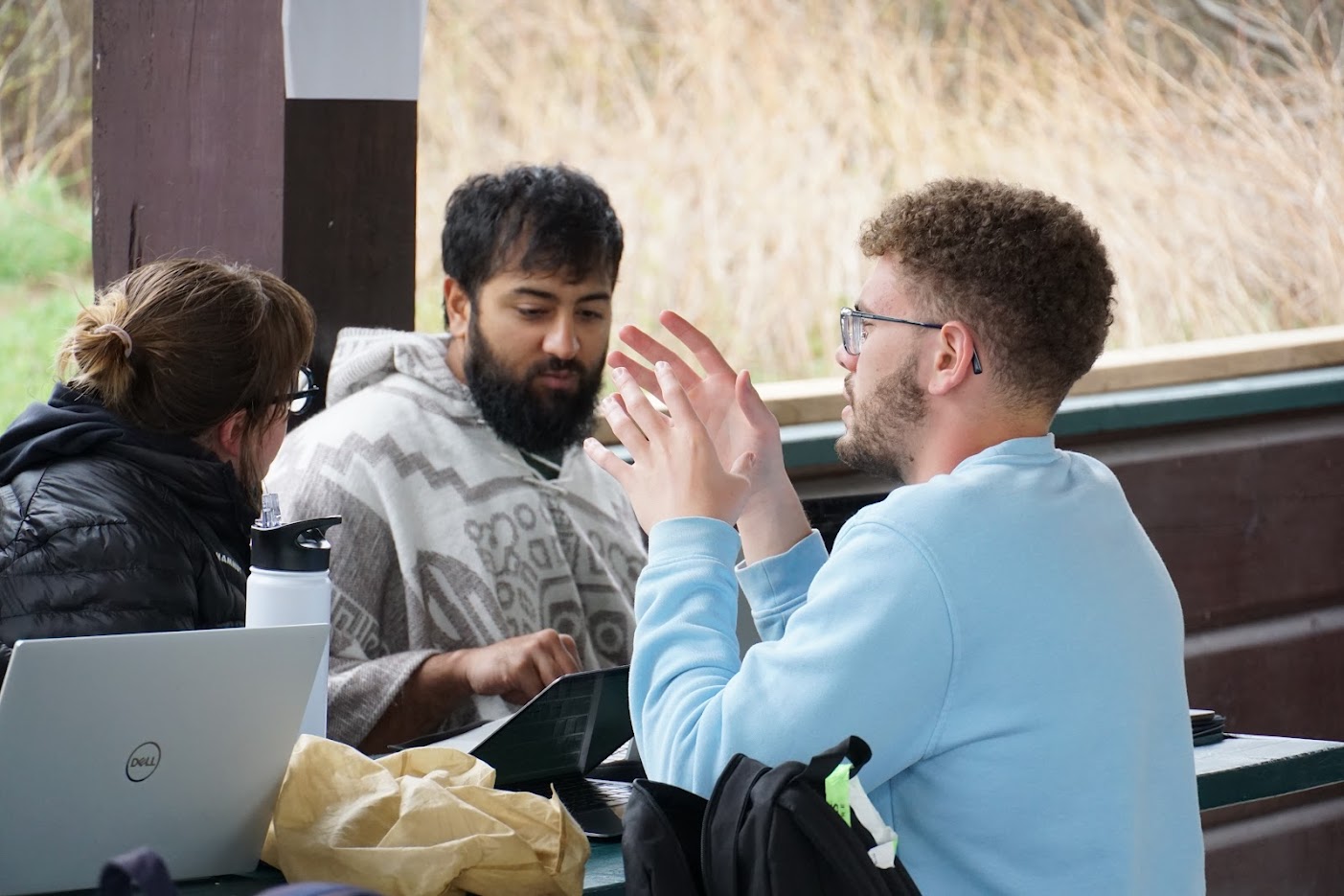Students discuss amongst themselves with a laptop open in front of them